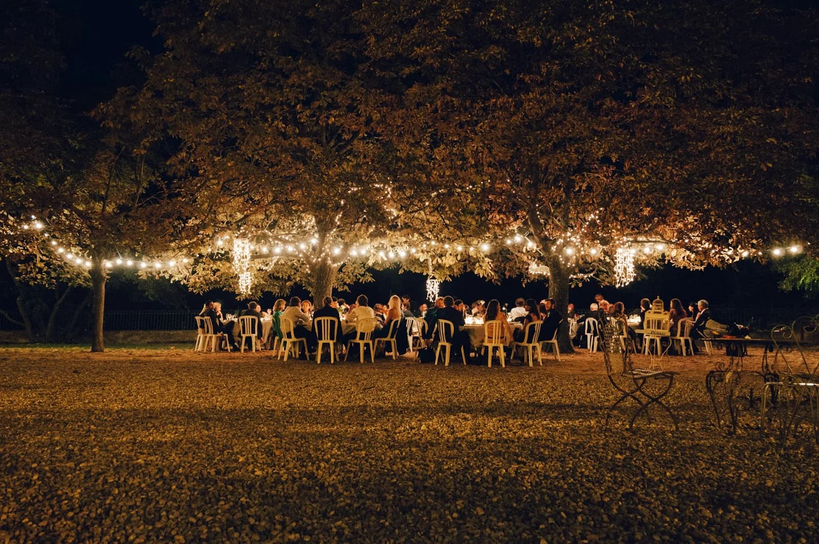 Evening wedding tables under strands of string lights outdoors